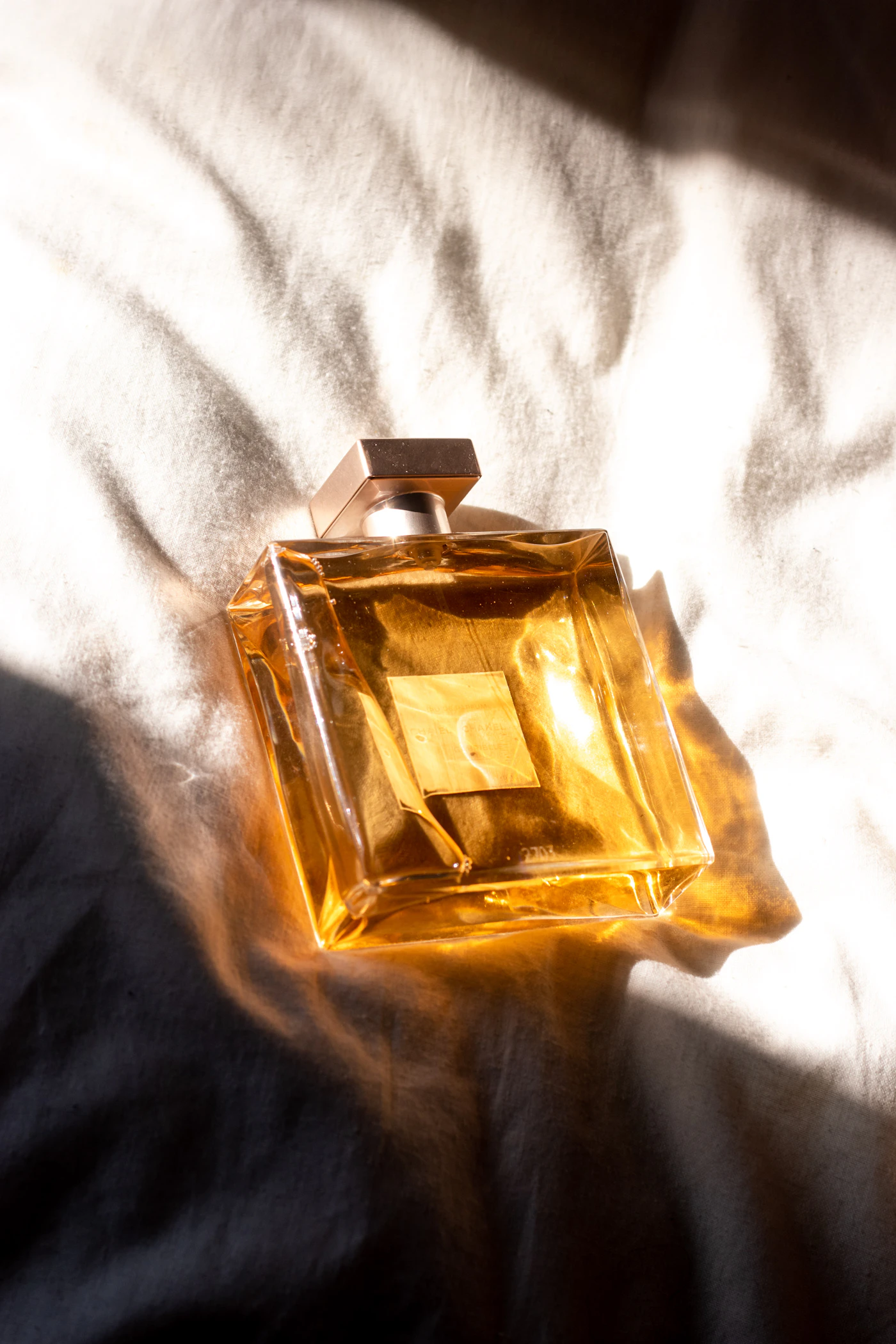 Flacon de parfum doré posé dans une lumière chaude