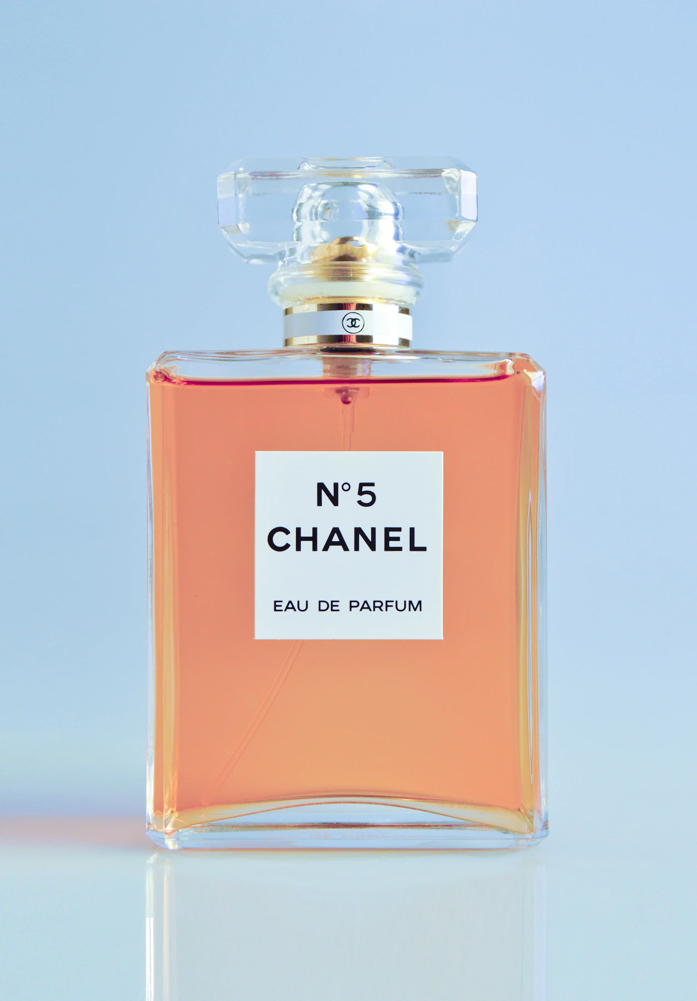 Flacon de parfum rose sur un fond bleu clair