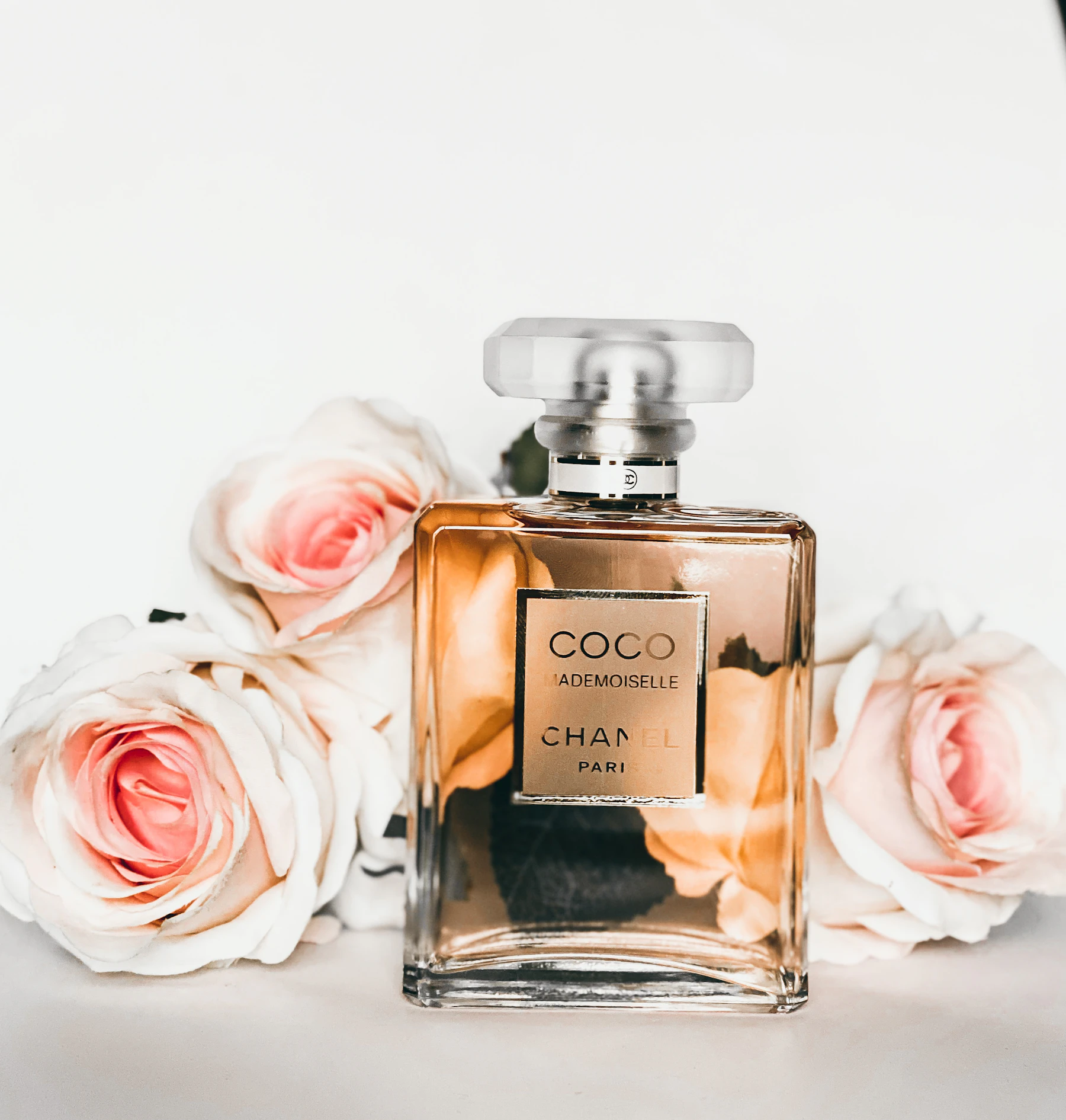 Flacon de parfum ambré entouré de roses claires